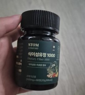 스톰 식이섬유정 1000 통을 손에 들고 있는 사진